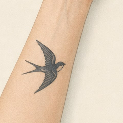 Illustration of a small dark swallow tattoo on a forearm before treatment